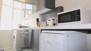 Moderni keittiö, jossa on mikroaaltouuni, leivänpaahdin ja astianpesukone.