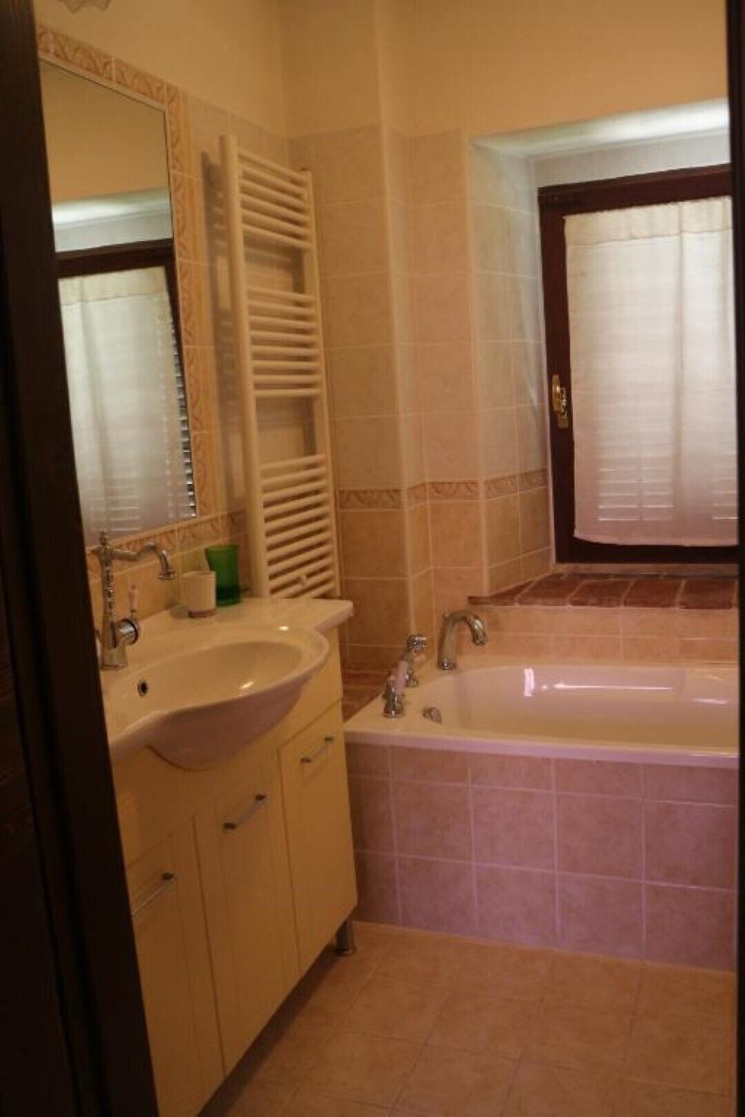 A bathroom with a sink, mirror, and bathtub.