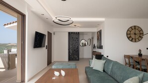 A modern living room with a sofa, coffee table, and a dining area with a table and chairs. - Anema Villa, a picture-perfect summer escape (Rethymno)