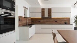 A modern kitchen with white cabinetry, a Bosch oven, and a wooden backsplash. - Anema Villa, a picture-perfect summer escape (Rethymno)