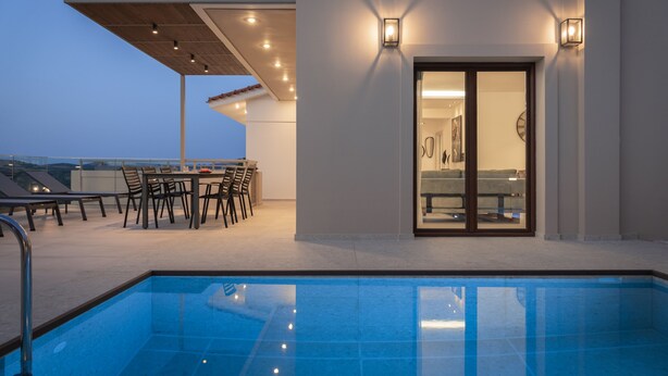 A rooftop pool area with a seating arrangement and a glass door leading to a bathroom. - Anema Villa, a picture-perfect summer escape (Rethymno)