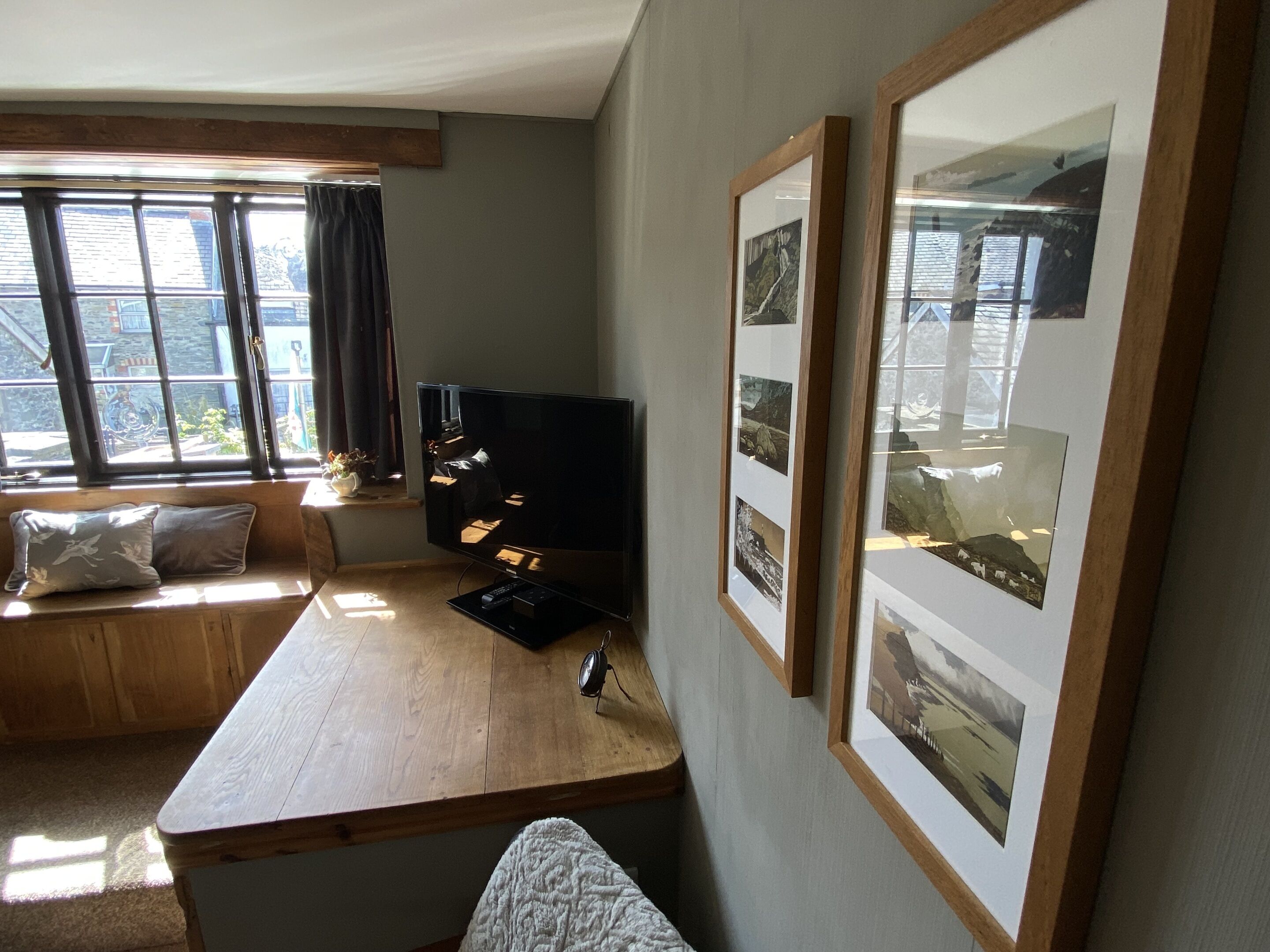 A cozy living room with a wooden table, a comfortable couch, and a large window with curtains.