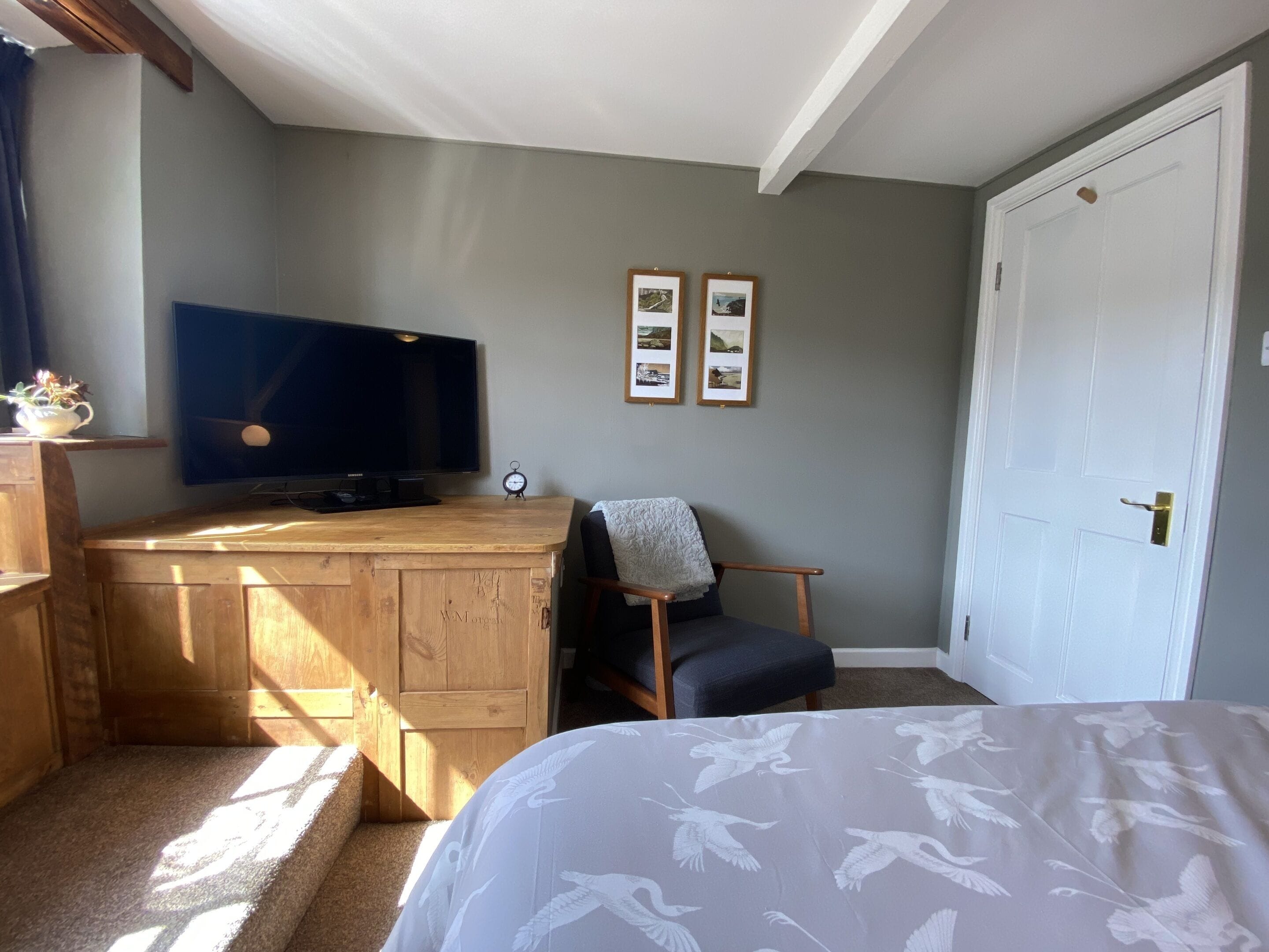 Une chambre à coucher avec un lit, un bureau en bois, une télévision et des tableaux encadrés accrochés au mur.