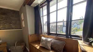 A cozy room with a wooden bench, a stone wall, and a window with curtains. - Tom's of Tregaron (Tregaron)