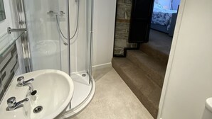 A modern bathroom with a glass shower enclosure, a sink, and a toilet. - Tom's of Tregaron (Tregaron)