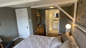Ein Schlafzimmer mit Bett, Schminktisch, Spiegel, Nachttisch und einem durchgehenden Türspalt sichtbaren Badezimmer.