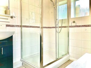 A modern bathroom with a glass-enclosed shower, a white sink, and a mirror above the sink.