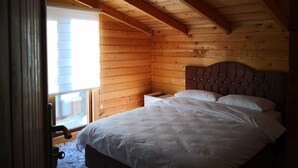 Ein Schlafzimmer mit Holzboden, einem Bett mit weißer Bettwäsche und einem Nachttisch.