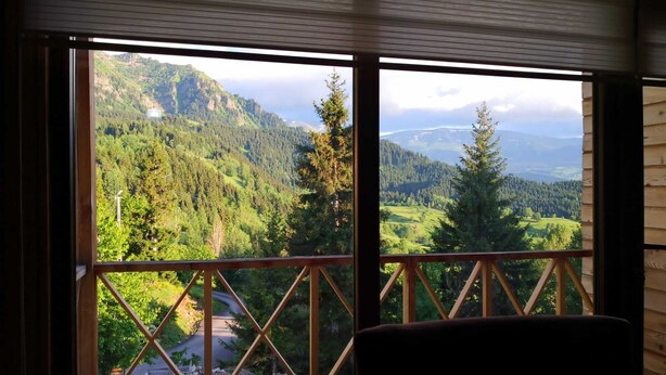 Ein Zimmer mit großem Fenster und Blick auf eine gebirgige Landschaft.