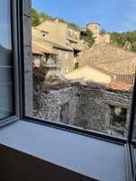 Vista desde una ventana que da a un edificio de piedra con techo de lajas y una torre.