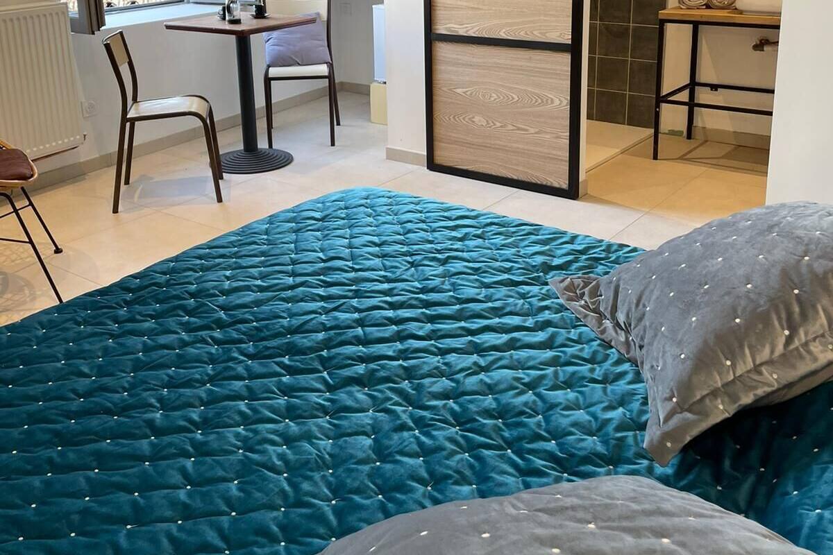 A bedroom with a large bed, a desk, and a sliding door leading to a bathroom.