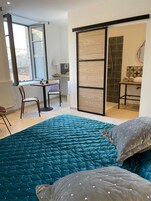 Un dormitorio con una cama grande, un escritorio y una puerta corrediza que da a un baño.