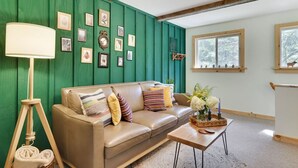 Una sala de estar acogedora con un panel verde, un sofá de cuero, una mesa de centro de madera y una lámpara de pie.
