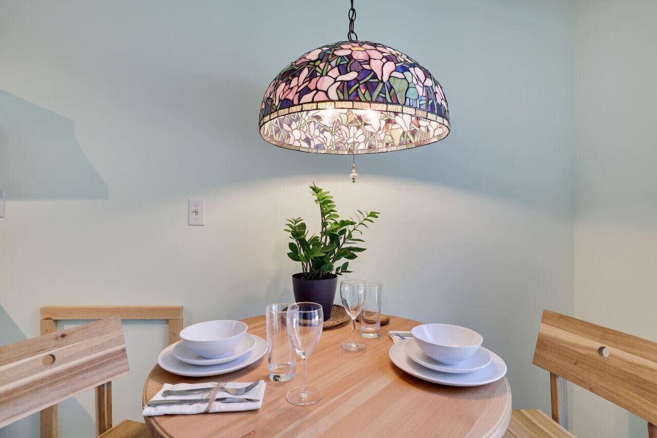 A dining table with white plates, glasses, and a potted plant.