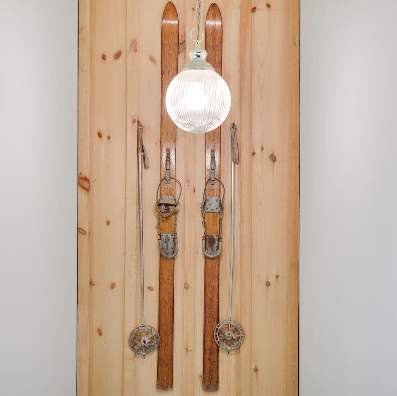 A wooden wall with skis and ski poles mounted vertically.