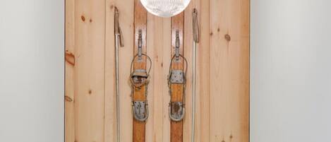 A wooden wall with skis and ski poles mounted vertically.