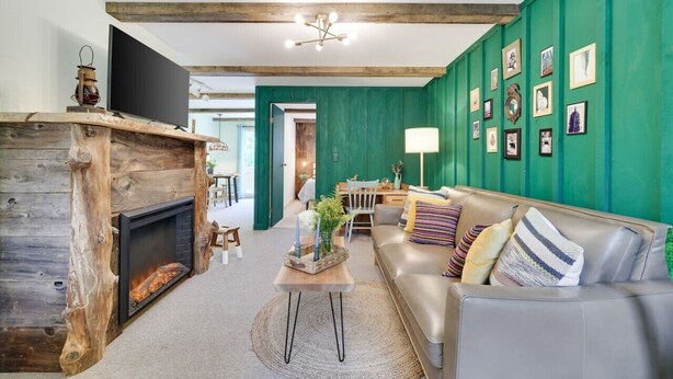 Una sala de estar acogedora con chimenea, un sofá y una pared verde de acento.