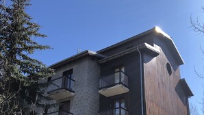 Un immeuble à plusieurs étages, doté de balcons, d’une façade en pierre et d’une partie en bois sur le côté droit.