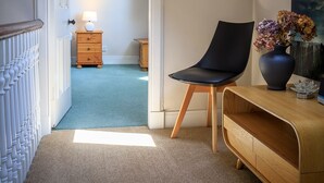 Une pièce avec un plafond en pente, une lucarne, une chaise, une commode et une lampe.
