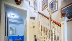 Un escalier avec une rampe blanche, un plancher en bois et un mur blanc orné de tableaux encadrés.