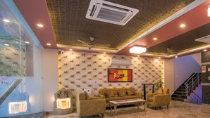 A lobby with a marble floor, a sofa, a coffee table, and a wall-mounted air conditioner. - Twin Towers  (Greater Noida)