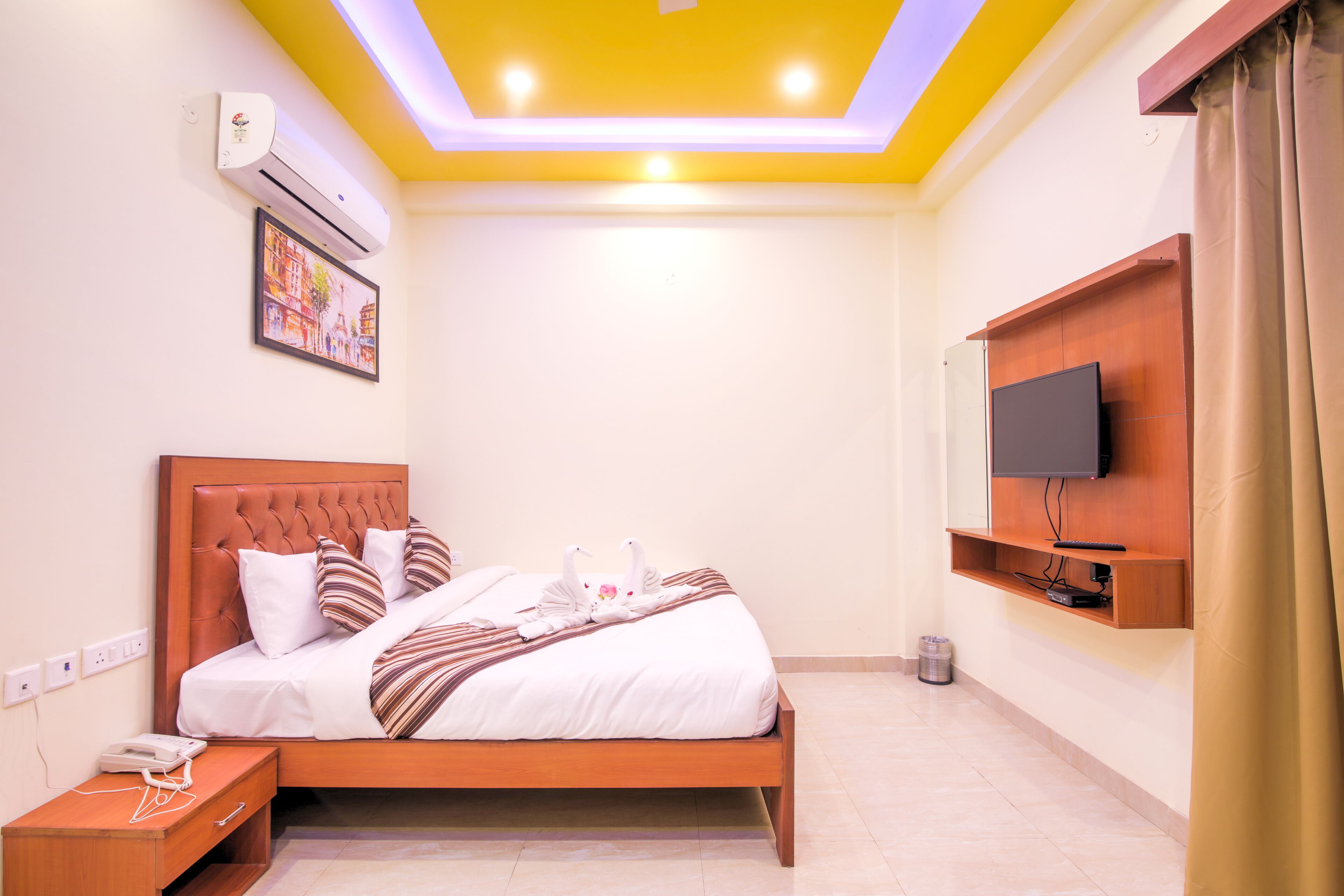 A neatly made bed with a striped blanket, a bedside telephone, and a wall-mounted TV.