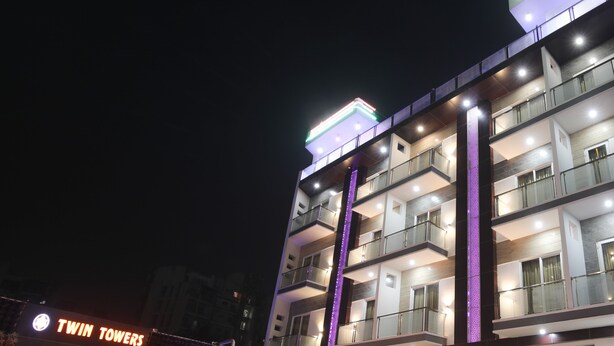 A modern hotel with multiple floors, outdoor seating area, and illuminated signage. - Twin Towers  (Greater Noida)