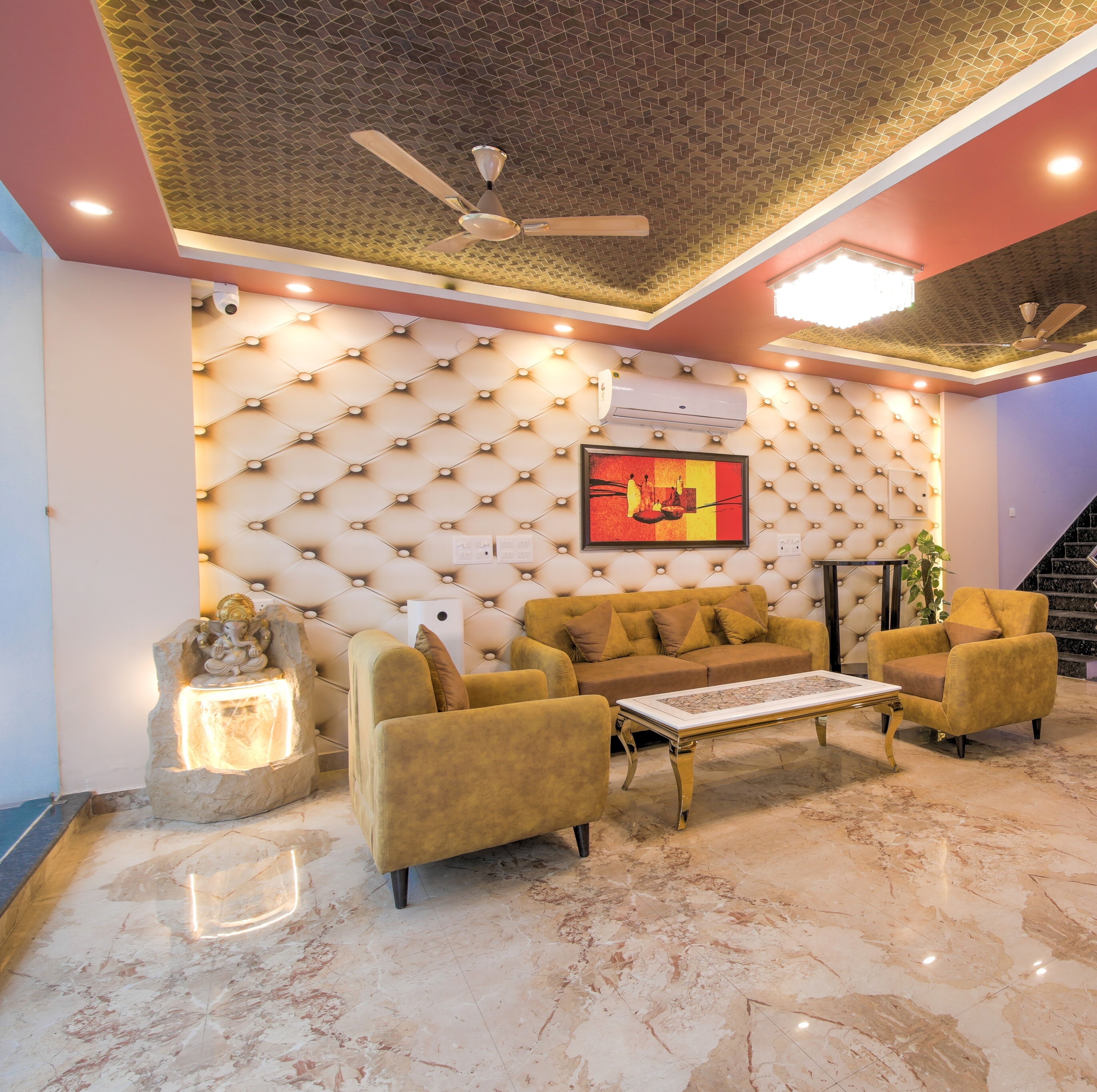 A modern living room with a tufted wall, a sofa set, a coffee table, and a ceiling fan.