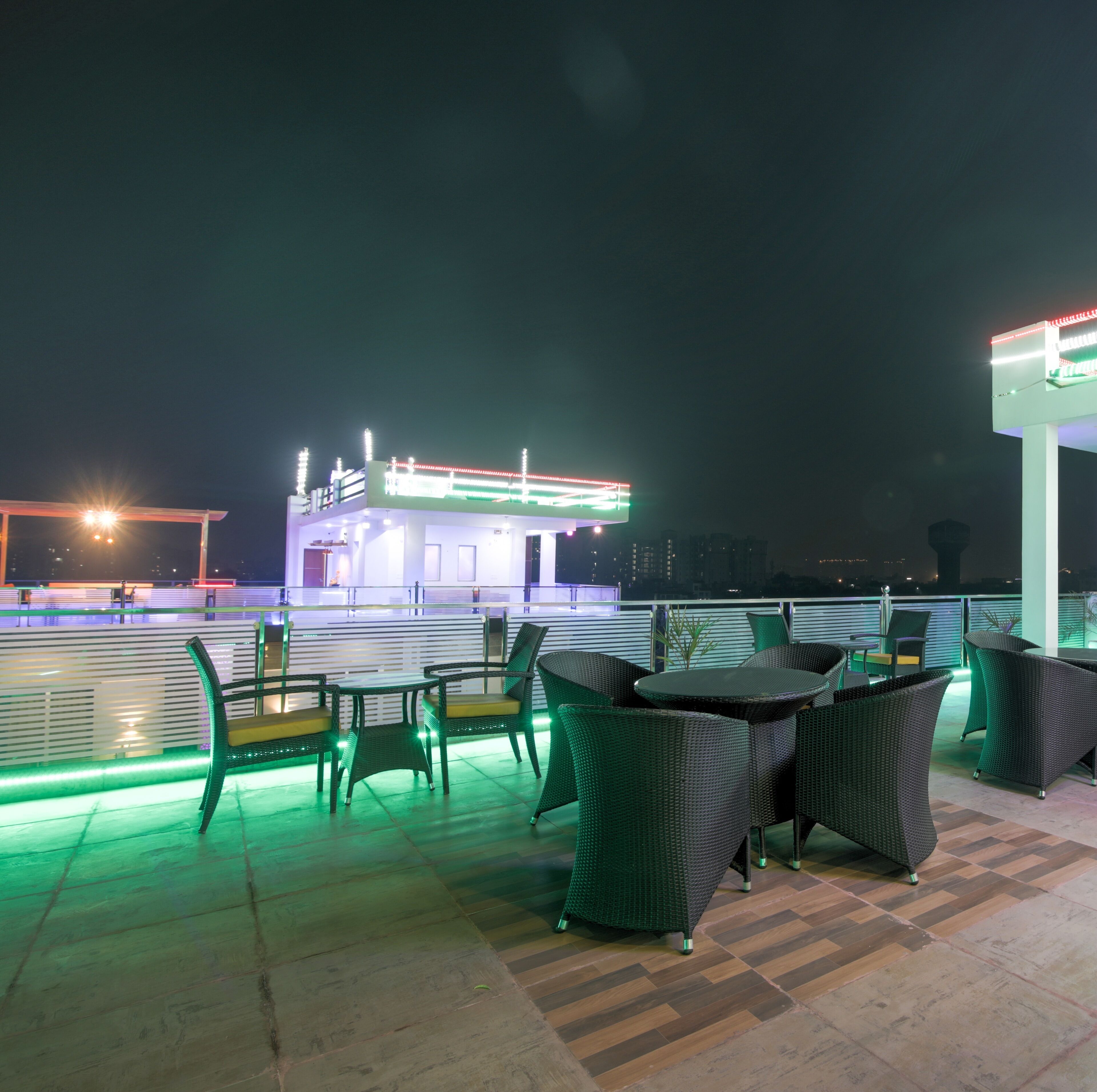 An outdoor seating area with wicker furniture and a view of a brightly lit building in the background.