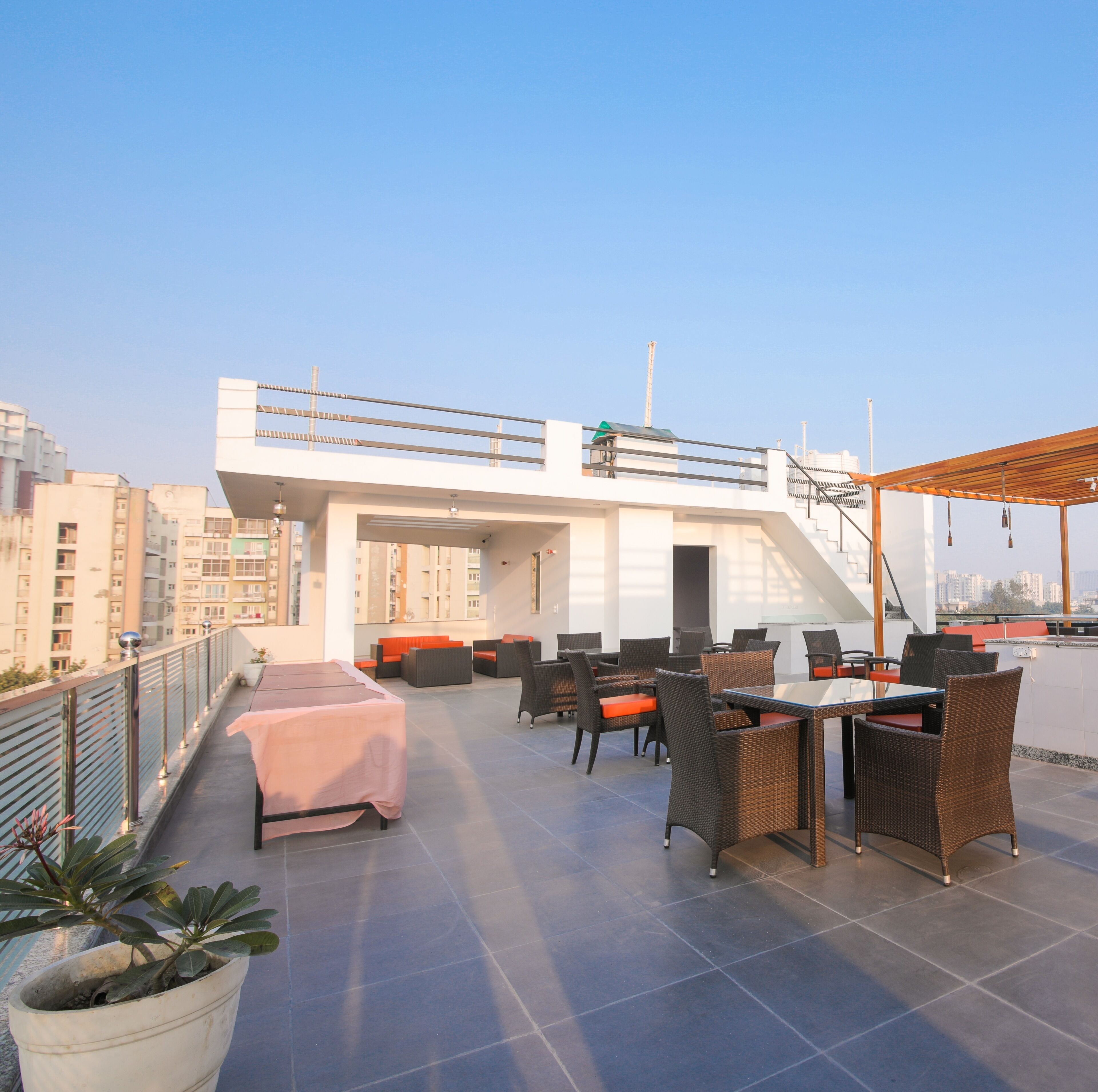 A rooftop terrace with outdoor seating, a covered area, and a view of surrounding buildings.