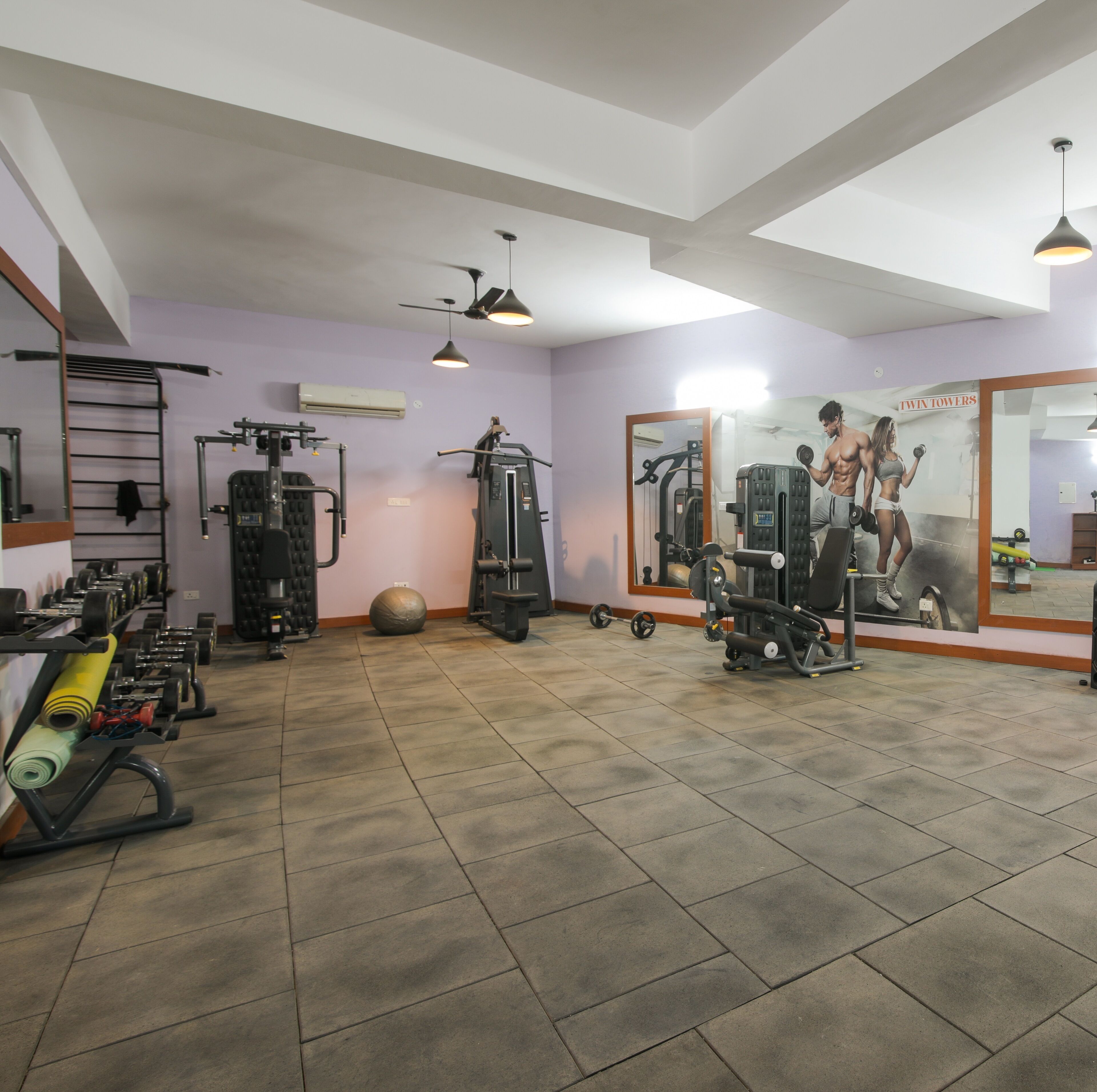 Un gimnasio con equipo de ejercicio, un espejo grande y un ventilador de techo.