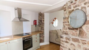 A modern kitchen with a built-in oven, a stainless steel range hood, and a wooden countertop. - Ramsey Cottage (Haverfordwest)