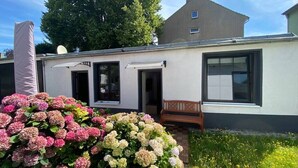Moderni rakennus, jossa on valkoinen julkisivu, suuret ikkunat ja ulkona oleva penkki.