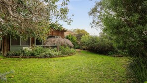 Une maison avec un jardin, une toiture de chaume et une grande variété de plantes.