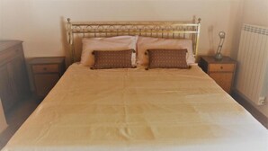 Una cama individual con cabecera de metal, dos almohadas, una mesita de noche y una lámpara de noche.