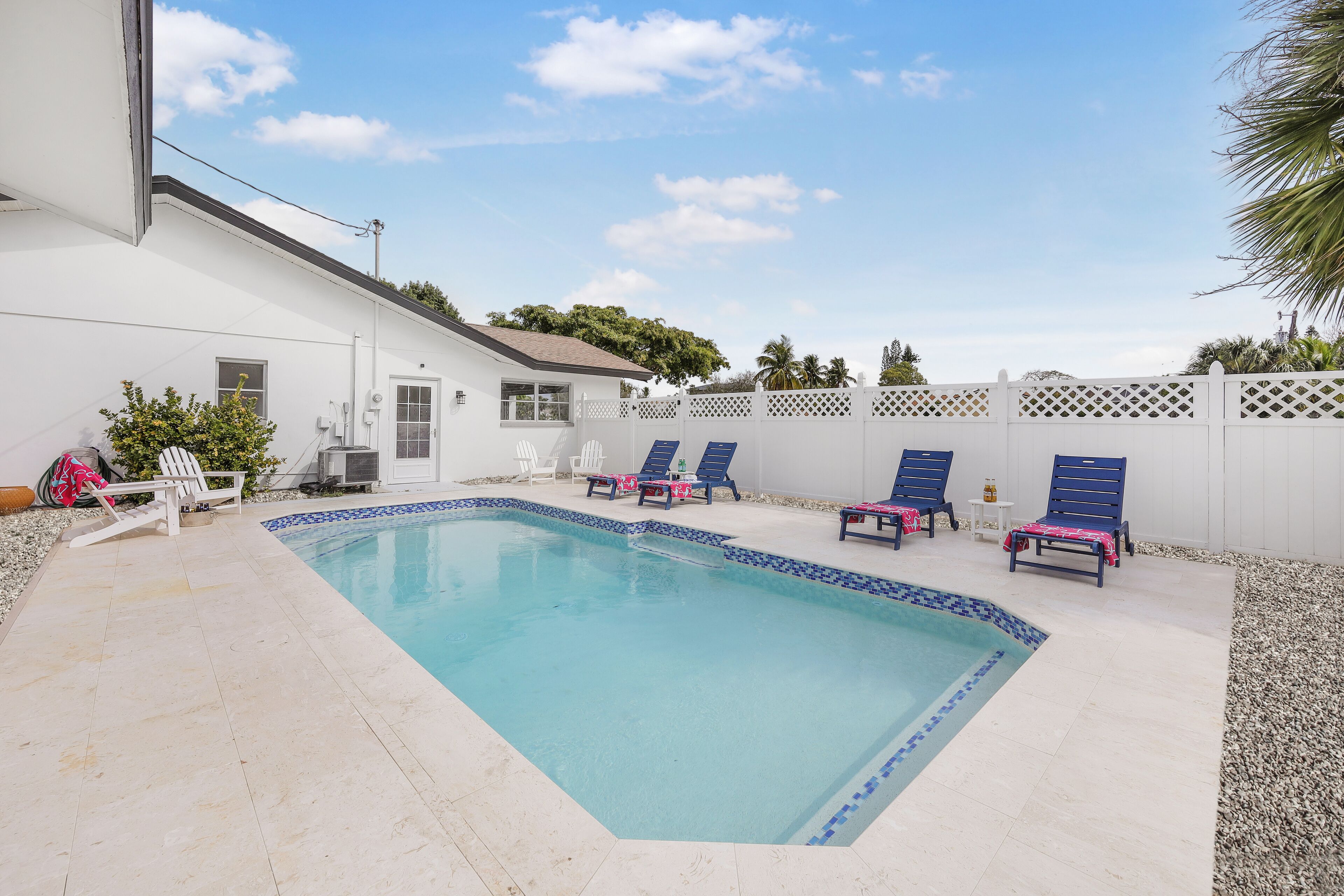 Une piscine avec des chaises longues et une clôture blanche.