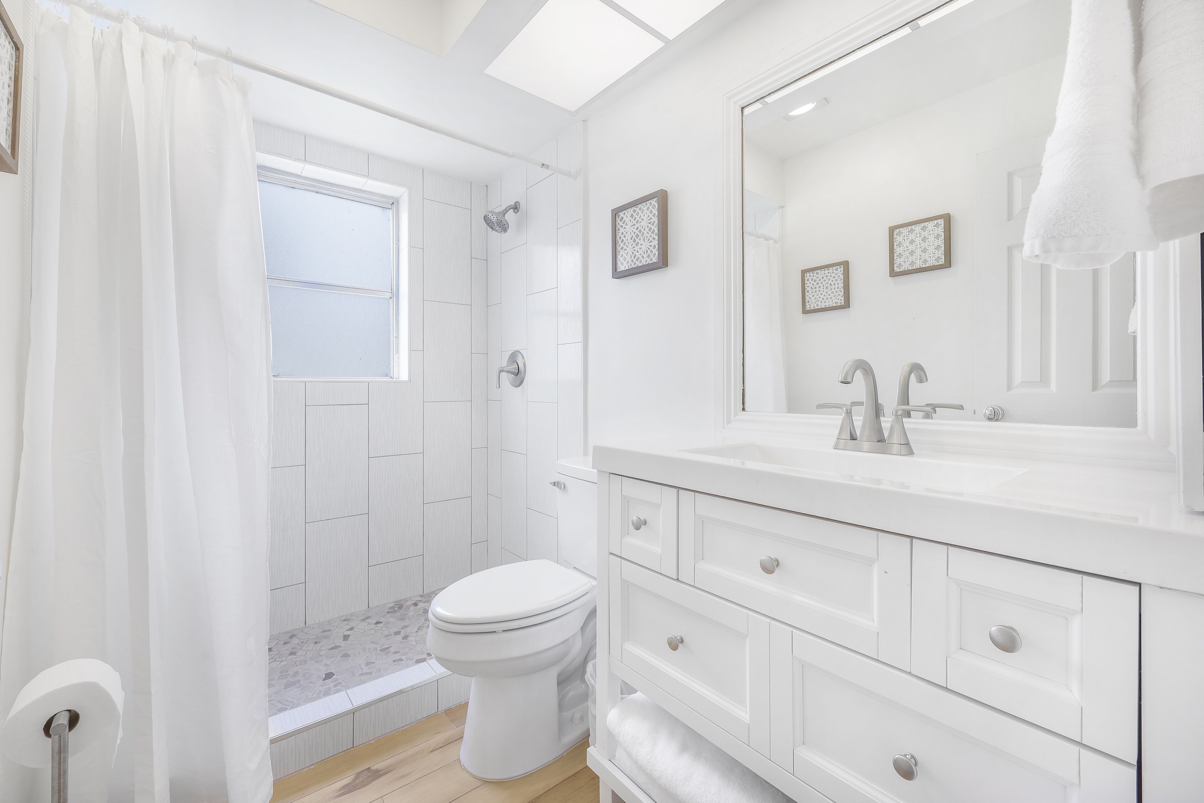 Une salle de bain moderne équipée d’une douche, de toilettes et d’un meuble-lavabo avec un grand miroir.