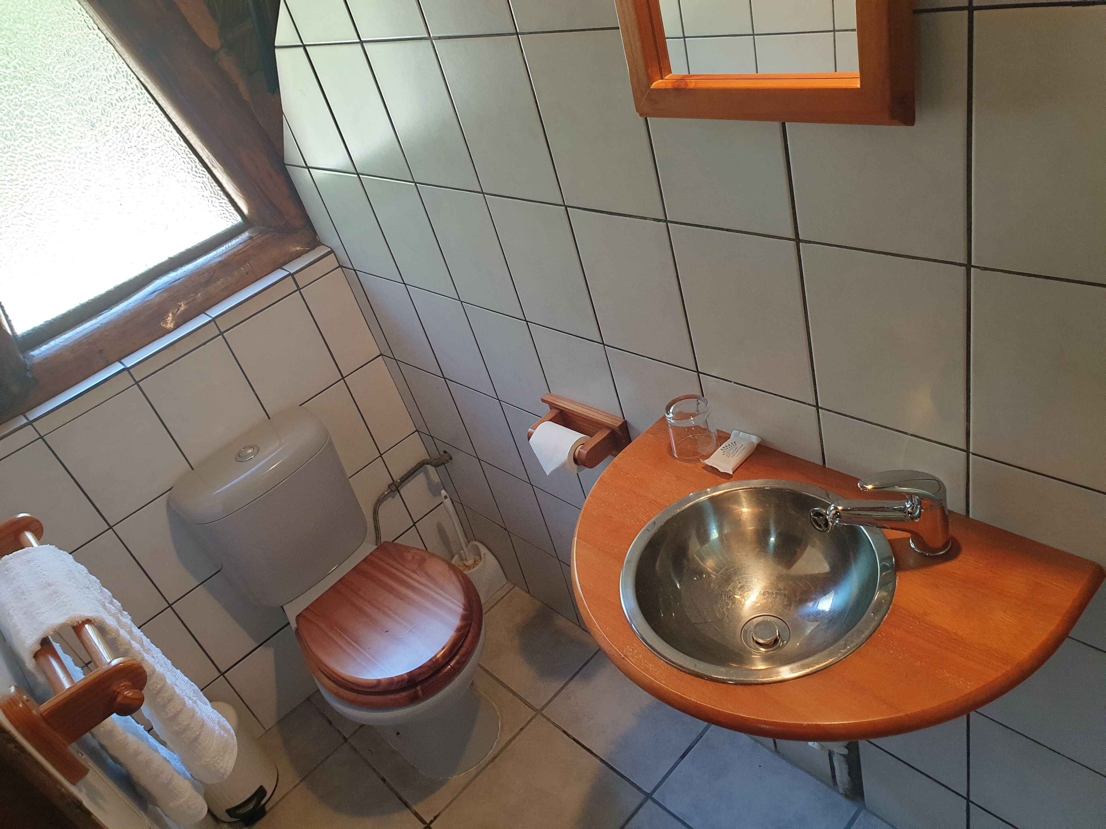 Un baño con inodoro, lavamanos y ventana.