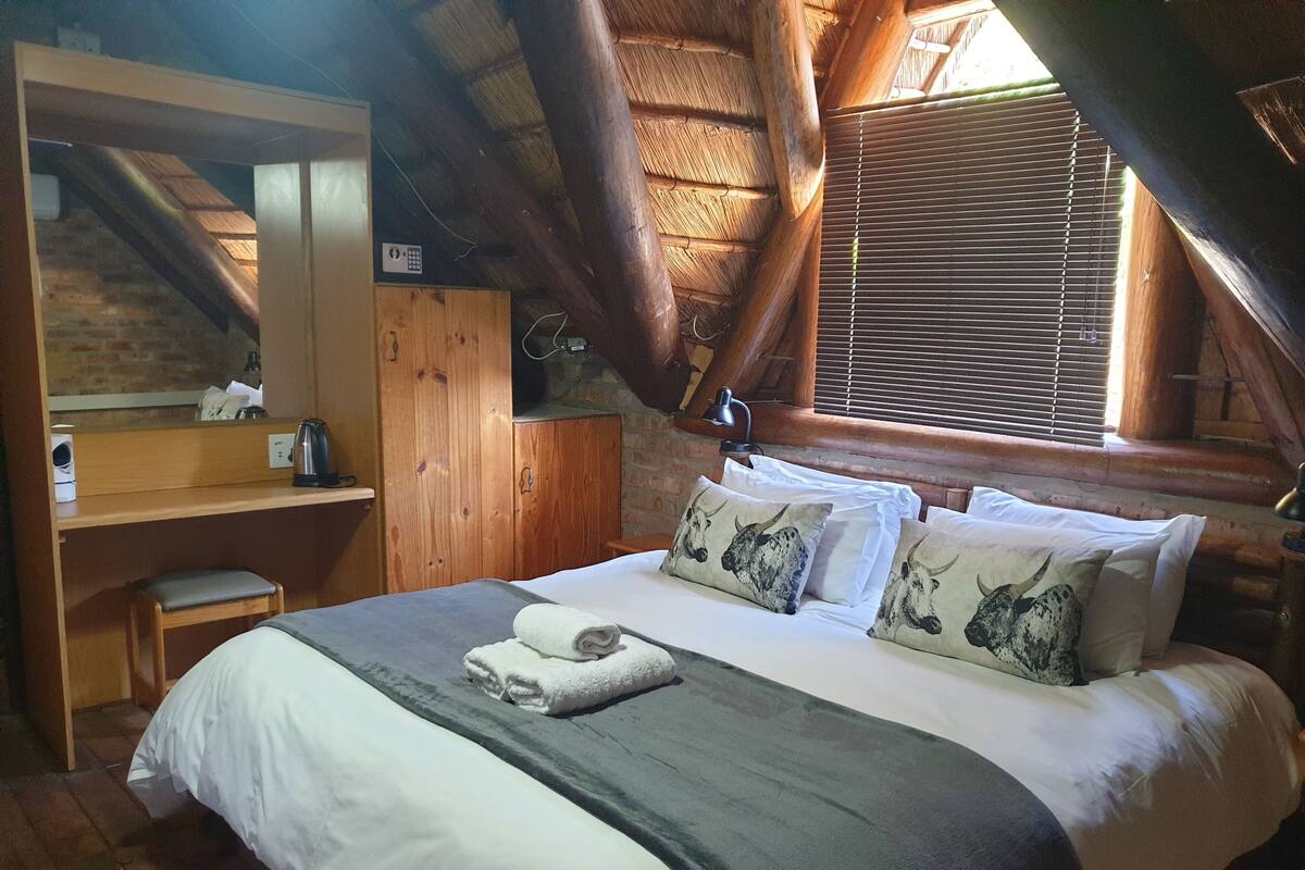 A cozy room with a bed, a desk, and a window with blinds.
