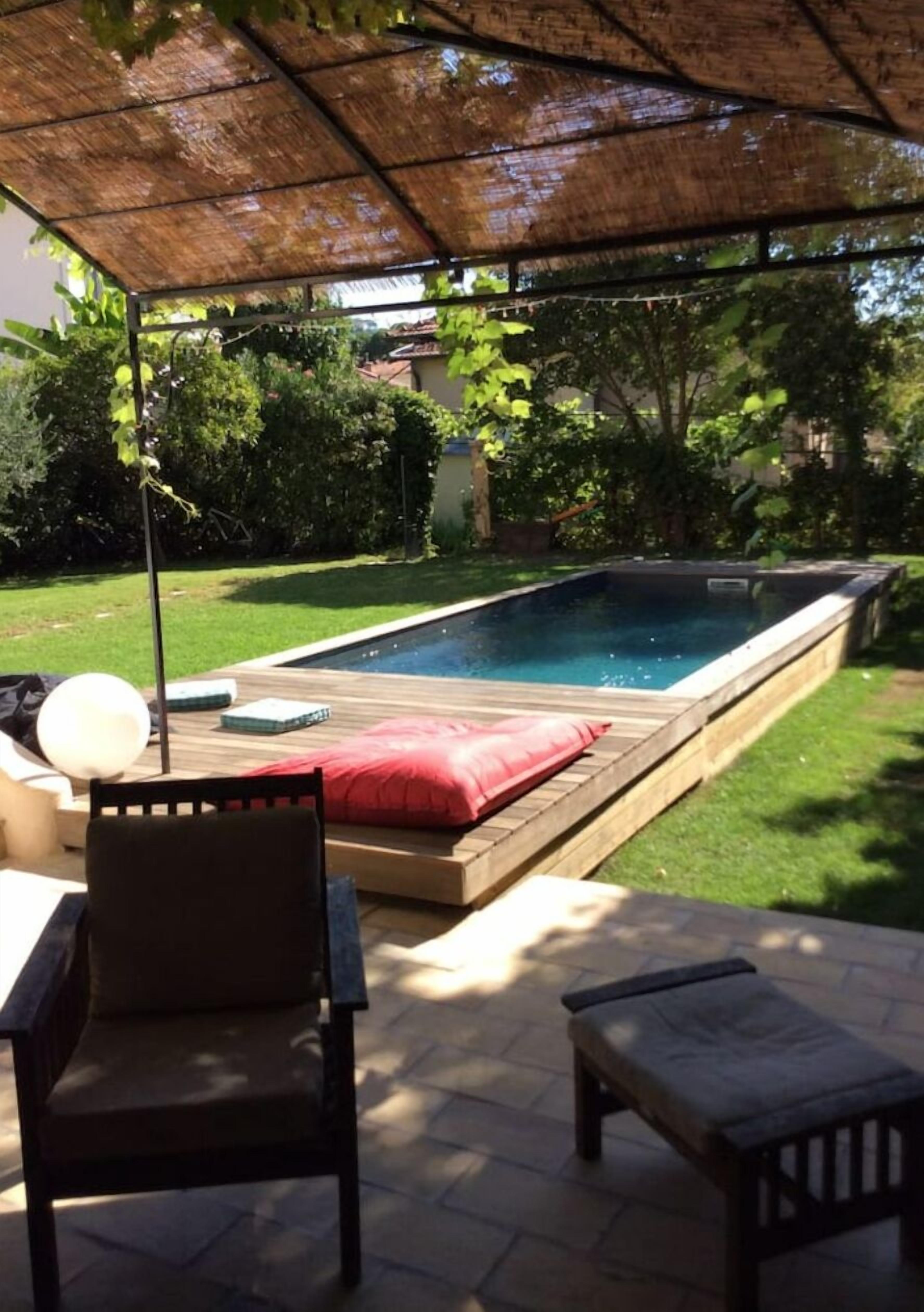 Un cortile con piscina, un patio coperto e mobili da esterno.