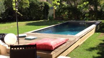 Un cortile con piscina, un patio coperto e mobili da esterno.