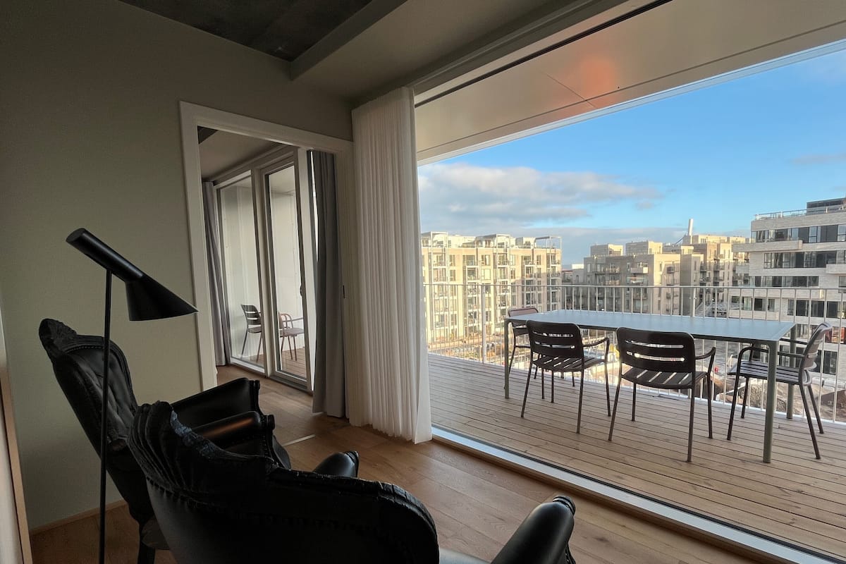 A modern apartment with a balcony, a dining table, and chairs.