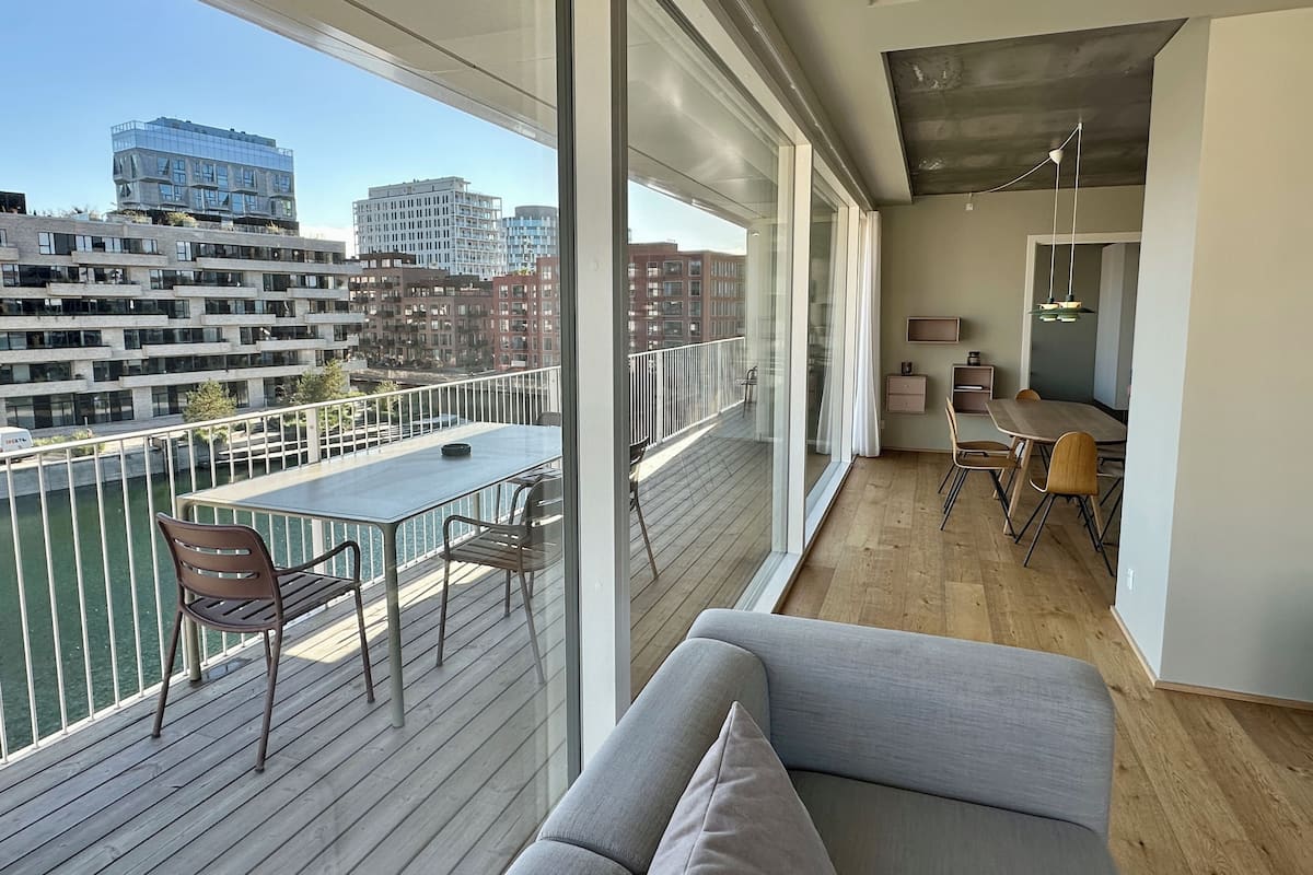 A modern apartment with a balcony, a dining area, and a living room with a sofa.