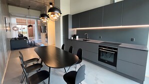 Una cocina moderna con comedor, que cuenta con una mesa grande, sillas, armarios empotrados e iluminación colgante.