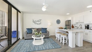 Una cocina moderna con armarios blancos, una isla central y un comedor con mesa de vidrio.