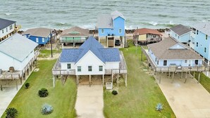 Rannikkoalue, jossa on asuintaloja paalujen varassa, laituri ja näkymä merelle.