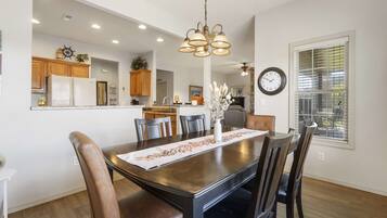 A dining area with a dark wooden table, leather chairs, and a chandelier.