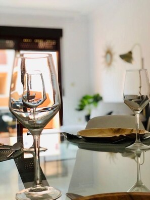 A dining table with two wine glasses and a plate, set in a room with a window and a plant in the background. - PUSHE Playa Granada Beach&Golf 2 (Motril)