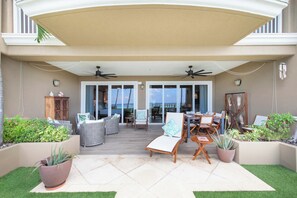 An outdoor patio with a covered seating area, ceiling fans, and potted plants.