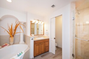 A bathroom with a bathtub, a vanity with a mirror, a toilet, and a shower area.